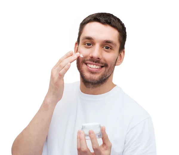 Beautiful smiling man applyin cream — Stock Photo, Image