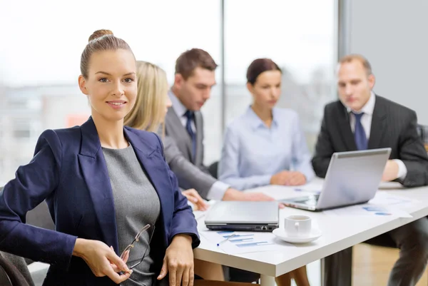 Businesswoman with glasses with team on the back — Stock Photo, Image