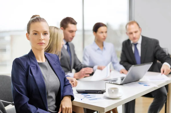 Zakenvrouw in kantoor met team op de rug — Stockfoto