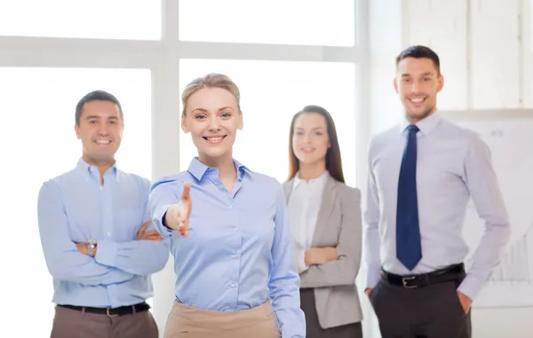 Empresária sorridente no cargo com equipe nas costas — Fotografia de Stock