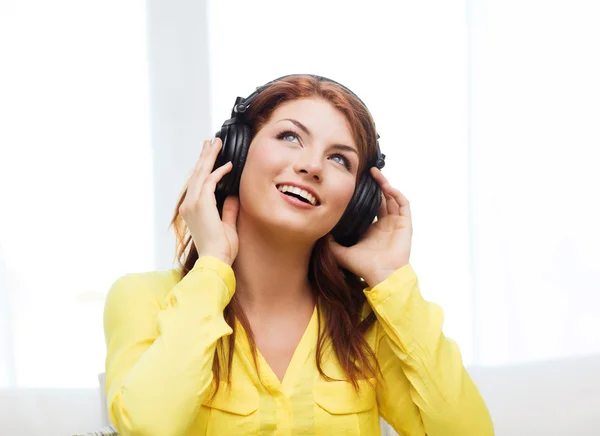 Sonriente chica joven en los auriculares en casa — Foto de Stock