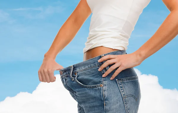 Närbild på kvinnliga visar stora jeans — Stockfoto