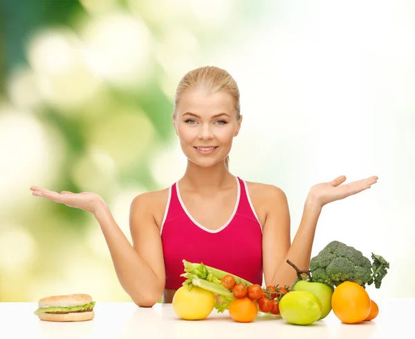 Mulher sorridente com frutas e hambúrguer — Fotografia de Stock