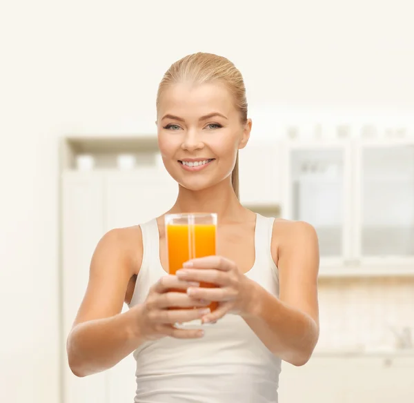 Mulher sorridente segurando vidro de suco de laranja — Fotografia de Stock