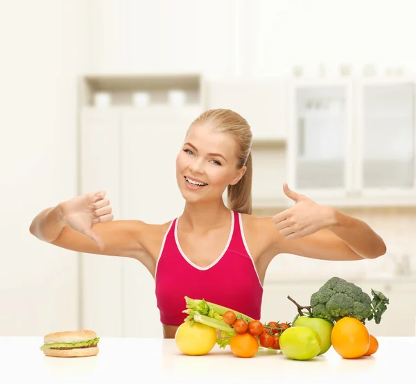 Mulher com frutas e hambúrguer comparando alimentos — Fotografia de Stock