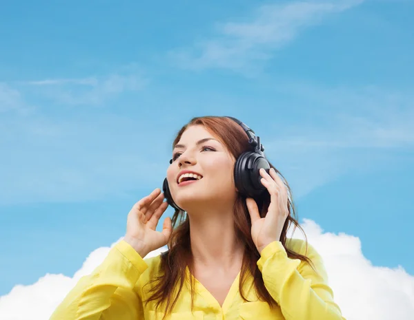 Sonriente chica joven en los auriculares en casa — Foto de Stock