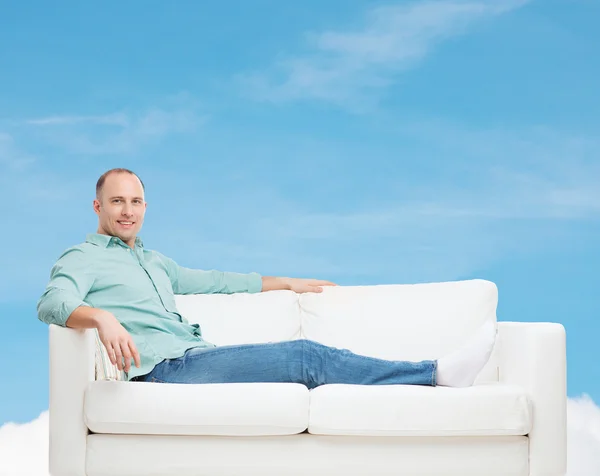 Lächelnder Mann auf Sofa liegend — Stockfoto