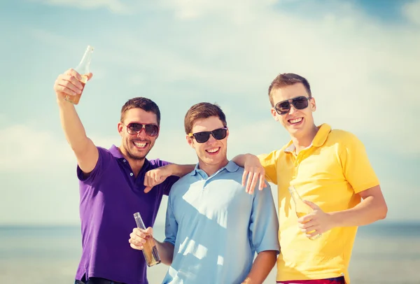 Friends on the beach with bottles of drink — Stock Photo, Image