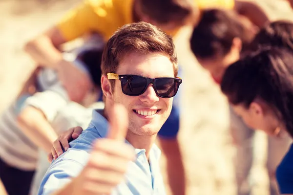 Mann mit Freunden am Strand zeigt Daumen hoch — Stockfoto