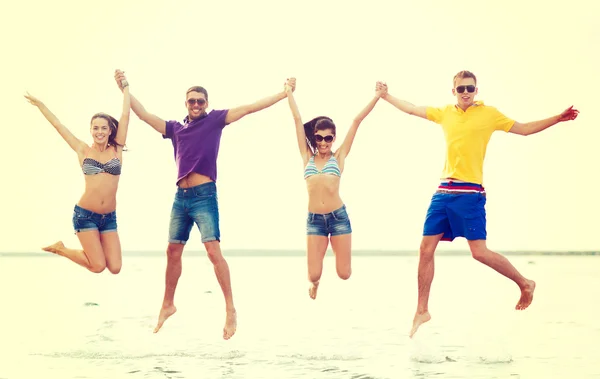 お友達やカップル、ビーチ上にジャンプのグループ — ストック写真
