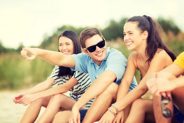 Grupo de amigos apontando para algum lugar na praia — Fotografia de Stock