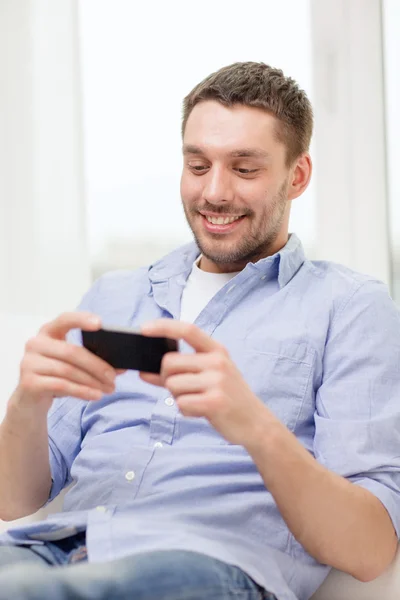 Sorrindo homem com smartphone em casa — Fotografia de Stock