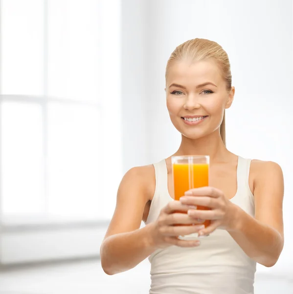 Mulher sorridente segurando vidro de suco de laranja — Fotografia de Stock