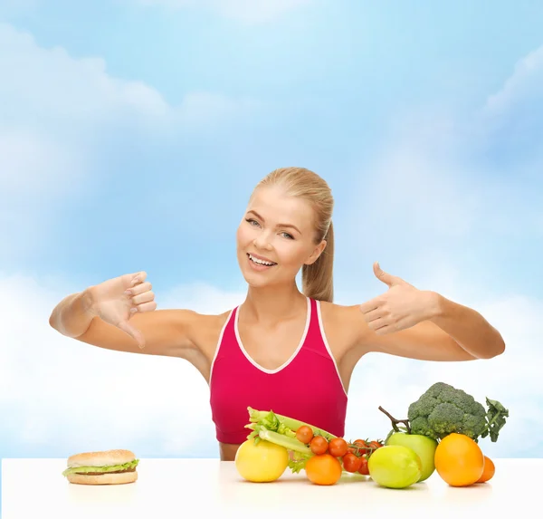 Mulher com frutas e hambúrguer comparando alimentos — Fotografia de Stock