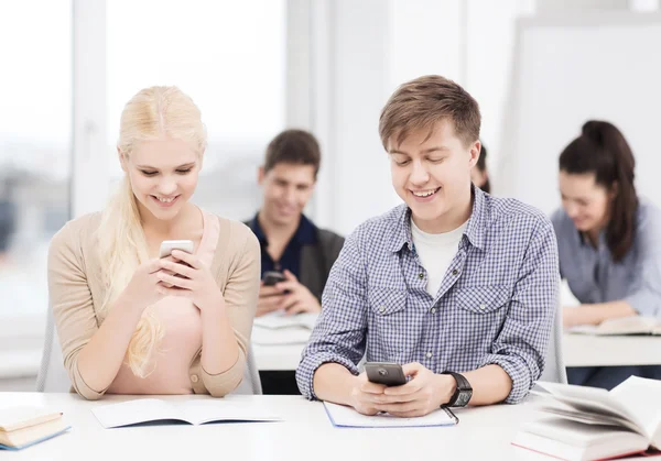 Studenti při pohledu do smartphone ve škole — Stock fotografie