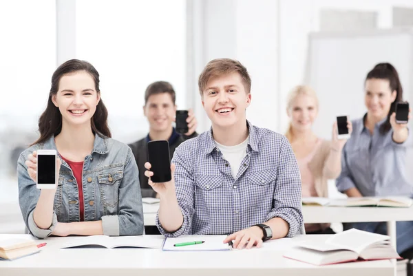 Studenti che mostrano schermi bianchi neri dello smartphone — Foto Stock