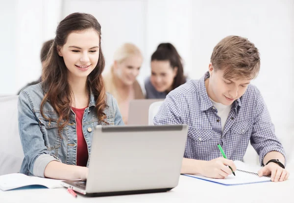 Estudiantes con laptop y cuadernos en la escuela — Foto de Stock