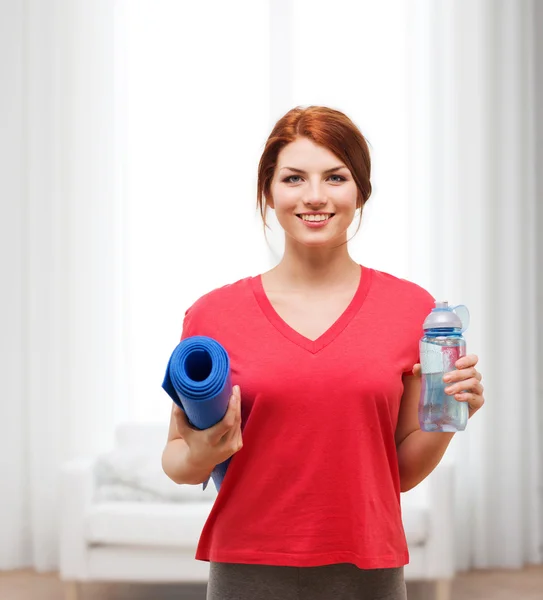 Улыбающаяся девушка с бутылкой воды после тренировки — стоковое фото