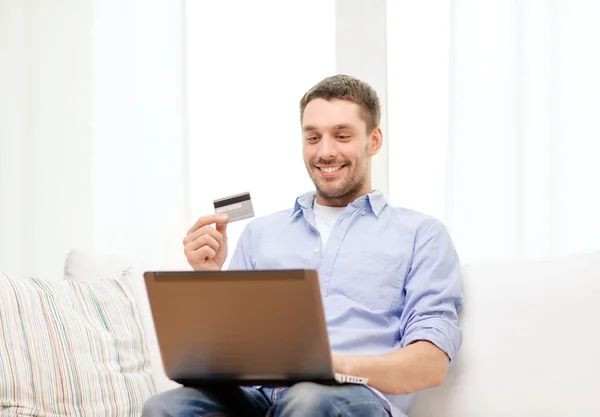 Homme souriant travaillant avec ordinateur portable et carte de crédit — Photo