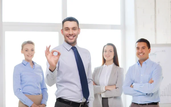 Hombre de negocios sonriente mostrando ok-sign en la oficina — Foto de Stock