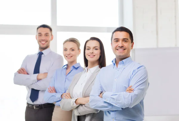 Empresário sorridente no cargo com equipe nas costas — Fotografia de Stock