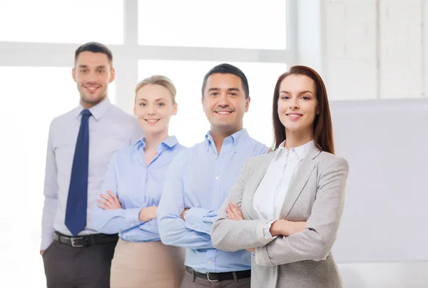 Empresária sorridente no cargo com equipe nas costas — Fotografia de Stock