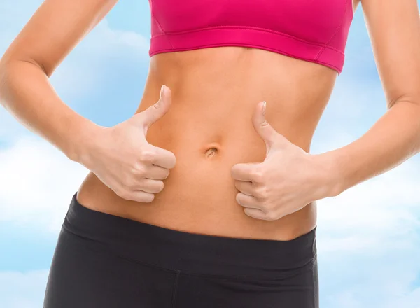 Close up de abdominais femininos e mãos mostrando polegares para cima — Fotografia de Stock