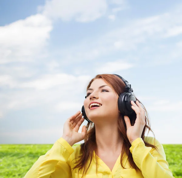 Sonriente chica joven en los auriculares en casa — Foto de Stock