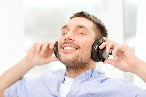 Joven sonriente con auriculares en casa — Foto de Stock