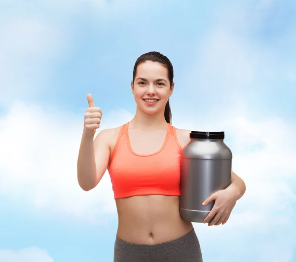 Teenage girl with jar of protein showing thumbs up — Stock Photo, Image