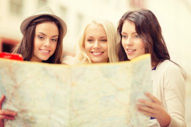 Beautiful girls looking into tourist map in city clipart