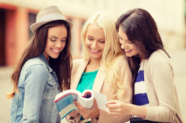 Beautiful girls looking into tourist book in city — Stock Photo, Image