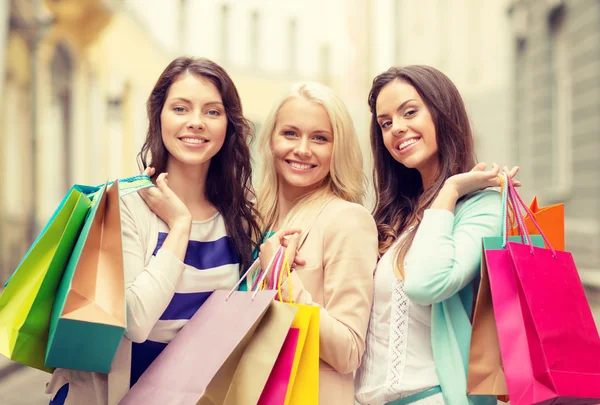 Três meninas sorridentes com sacos de compras em ctiy — Fotografia de Stock