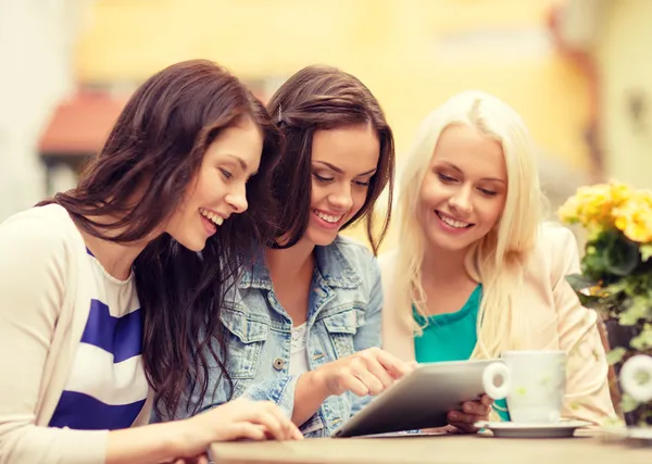 Drie mooie meisjes kijken naar tablet pc in café — Stockfoto