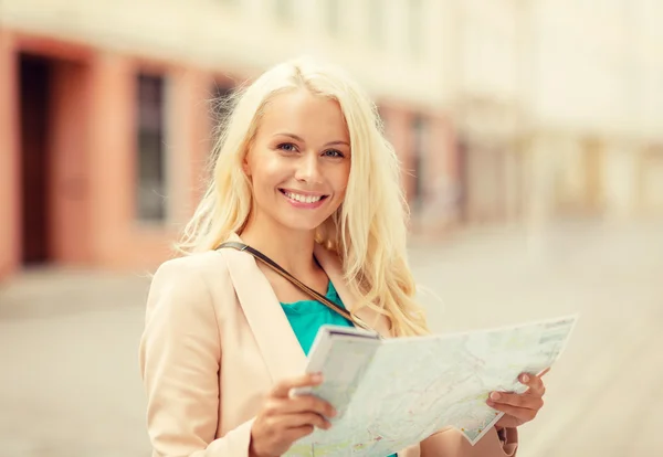 Menina sorridente com mapa turístico na cidade — Fotografia de Stock