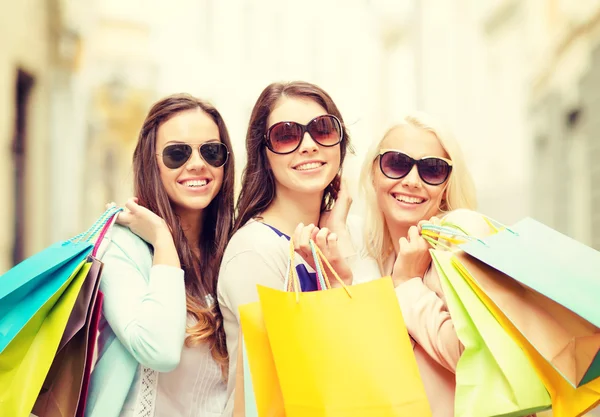 Three smiling girls with shopping bags in city Stock Picture