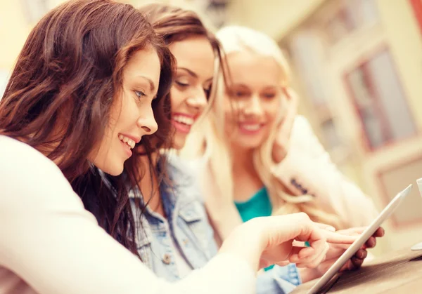 Three beautiful girls looking at tablet pc in cafe Stock Photo