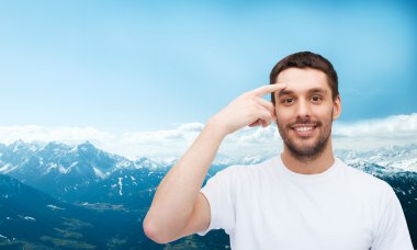 Smiling young handsome man pointing to forehead clipart