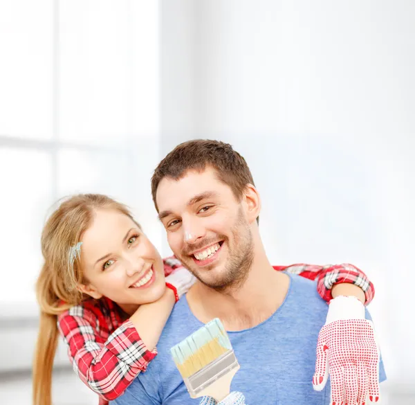 Smiling couple covered with paint with paint brush — Stock Photo, Image