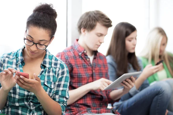 Students looking into devices at school — Stock Photo, Image