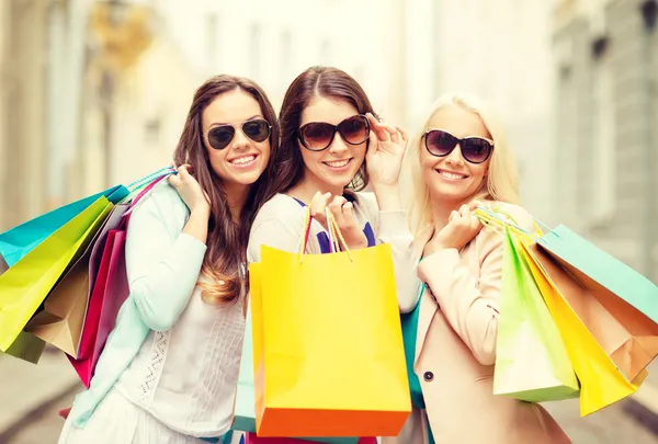 Três meninas sorridentes com sacos de compras em ctiy — Fotografia de Stock