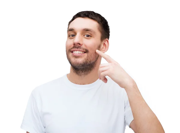 Smiling young handsome man pointing to cheek — Stock Photo, Image