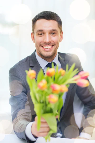 花の花束を与えること笑みを浮かべてのハンサムな男 — ストック写真