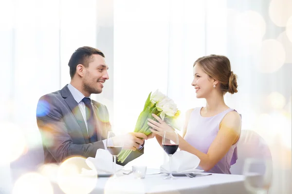 Uomo sorridente che dà mazzo di fiori al ristorante — Foto Stock