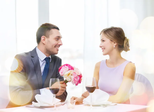 Sorrindo homem dando buquê de flores no restaurante — Fotografia de Stock