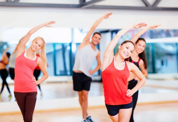 Grupo de personas sonrientes estirándose en el gimnasio —  Fotos de Stock