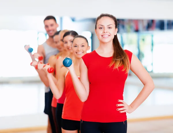 Grupp av leende människor med hantlar i gymmet — Stockfoto