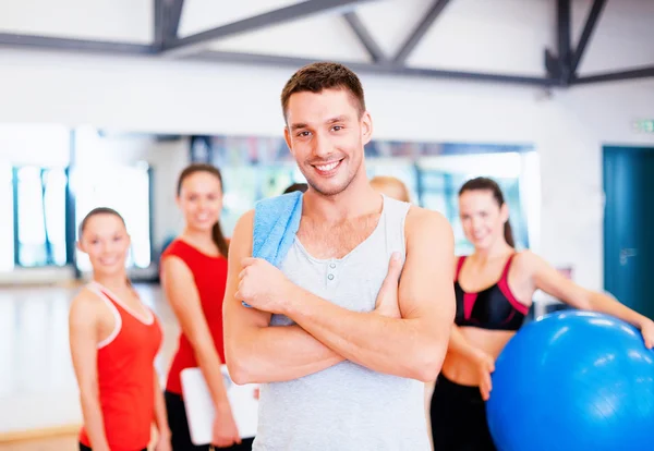 Uomo sorridente in piedi davanti al gruppo in palestra — Foto Stock