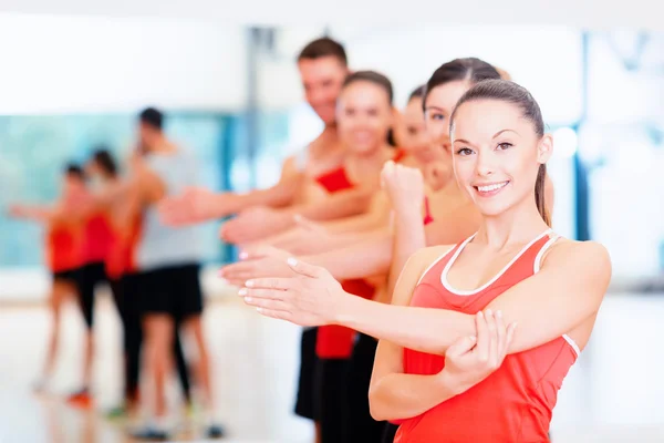 Grupp av leende människor sträcker sig i gymmet — Stockfoto
