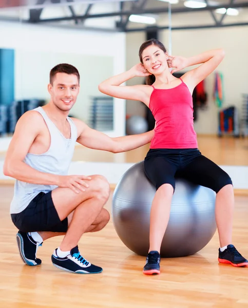 Entrenador masculino con mujer haciendo abdominales en la pelota —  Fotos de Stock